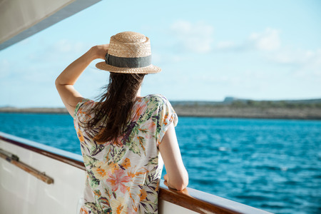 Young woman standing on board the ship and looking into the distanceの写真素材