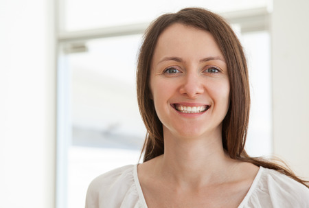 Portrait of a pleasant smiling young woman in a white interiorの写真素材