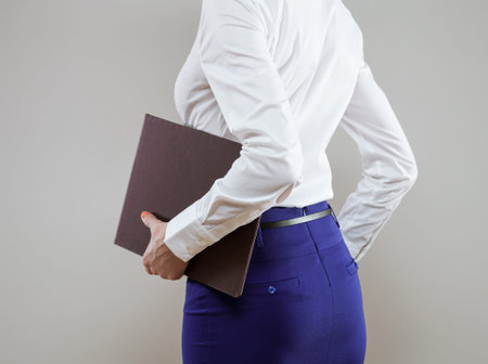 Unrecognizable young businesswoman going away, rear view; neutral backgroundの写真素材