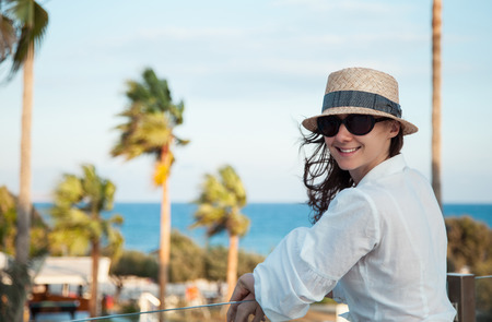 Portrait of a happy  young woman in a hat near the seaの写真素材