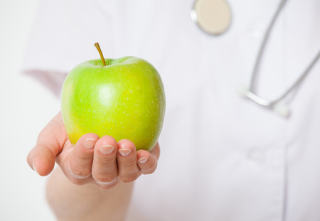 Doctor holding a fresh green apple, white backgroundの写真素材