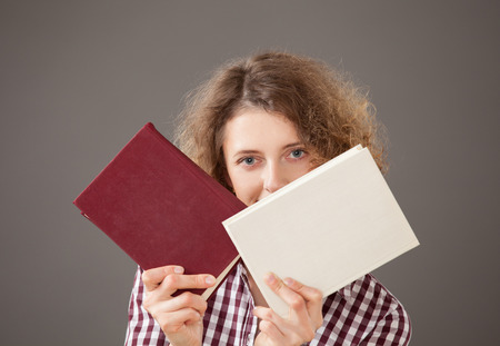 Portrait of a pretty young woman with a two books, gray backgroundの写真素材
