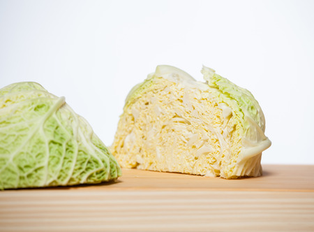 Savoy cabbage head cut in half on wooden boardの写真素材