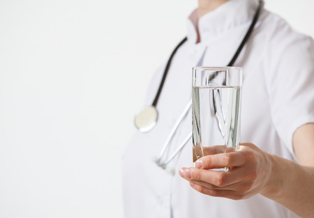 Doctor holding a glass with water, white backgroundの写真素材