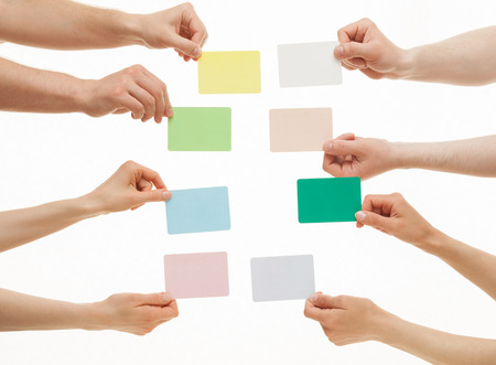 Many hands holding colorful paper cards on white backgroundの写真素材