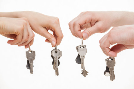 Four hands holding bunches of keys, white background