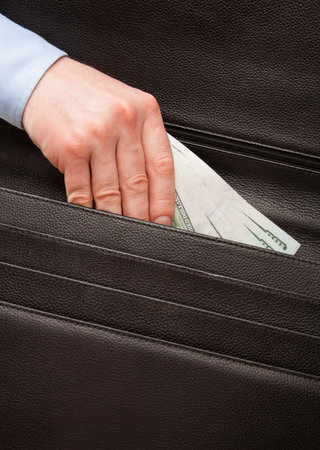 Unrecognizable businessman puts money in a briefcase - closeup shot