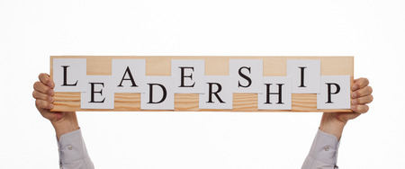Businessman holding a wooden plate with an inscription "Leadership", white backgroundの写真素材