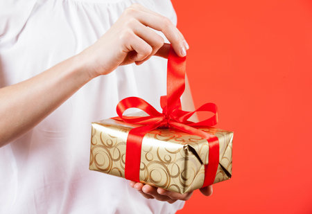Young woman holding a gift, red background