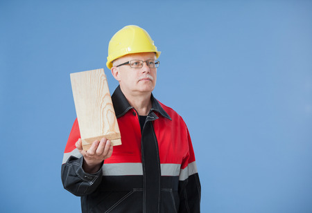 Mature builder holding a bar, blue backgroundの写真素材