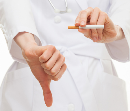 Doctor's hands showing disabling gesture and holding a cigarette, healthy lifestyle conceptの写真素材