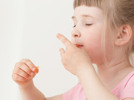 Pretty little girl eating an orange with enjoymentの写真素材