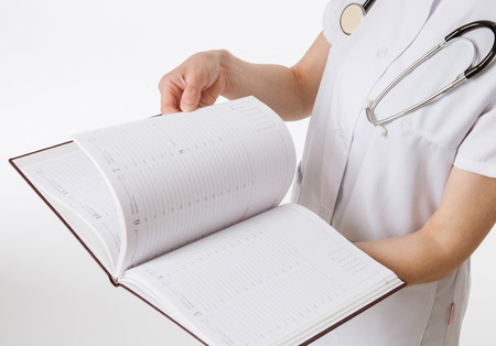 Unrecognizable doctor  turning over the pages, white backgroundの写真素材