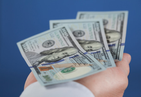 Businessman holding dollars on the palm, blue backgroundの写真素材