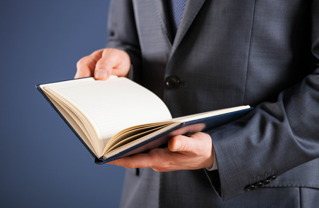 Businessman holding an opened book, dark backgroundの写真素材