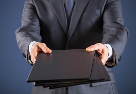 Businessman giving folders to you, closeup shotの写真素材