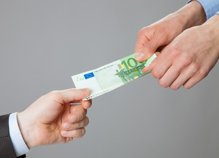 Business people hands exchanging money, closeup shot on grey backgroundの写真素材