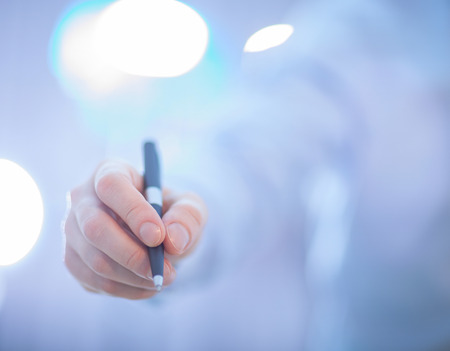 Businessman's hand holding a pen, blue backgroundの写真素材