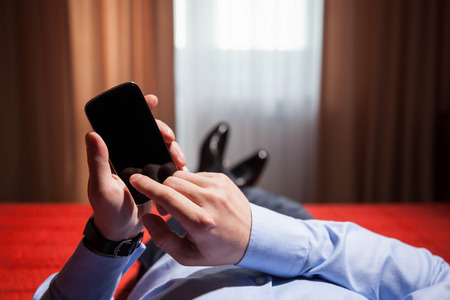 Relaxed businessman holding a mobile phone, closeup shotの写真素材