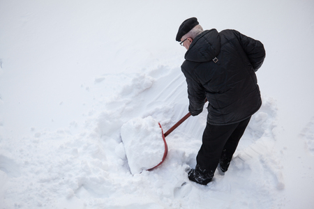 Man shovelling fresh snow  with a red shovelの写真素材