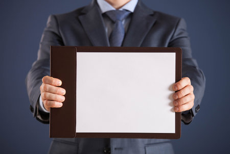 Businessman holding a clipboard with empty sheet of paper, dark  backgroundの写真素材
