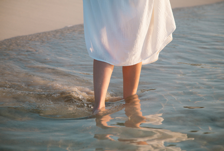 Legs of a young woman walking along the seacoastの写真素材