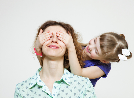 Happy daughter closing eyes her mother, neutral backgroundの写真素材