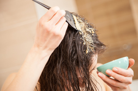 Woman applying mask to hair roots to make them grow stronger and faster and to prevent hairlossの写真素材