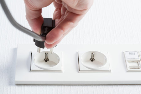 Male hand puts plug in the socket, closeup shot
