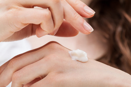 Closeup shot of woman hands applying moisturizing hand cream