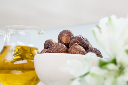 Closeup of a glass jug with olive oil and a bowl with soap berries - concept of natural haircareの写真素材