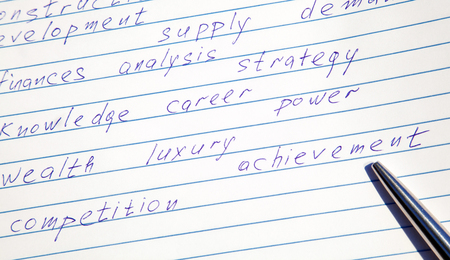 Pen pointing to the word "achievement" written among motivational words in a copybookの写真素材