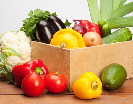 Assortment of fresh organic vegetables and fruits in a wooden box; tomato, aubergine, custard marrow, onion, cucumber, sweet pepper, parsley, leek, cauliflower, avocado - fresh ingredients for cookingの写真素材