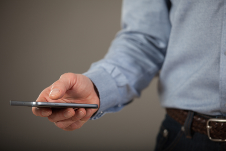 Unrecognizable young man using smartphone, dark gray backgroundの写真素材