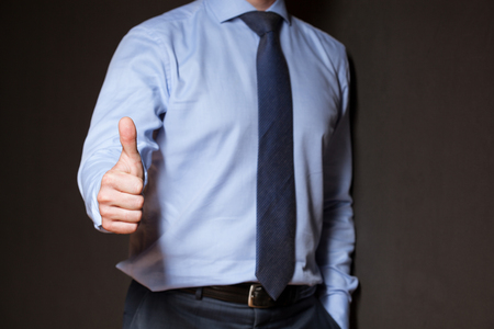 Unrecognizable businessman showing thumb up, gray backgroundの写真素材