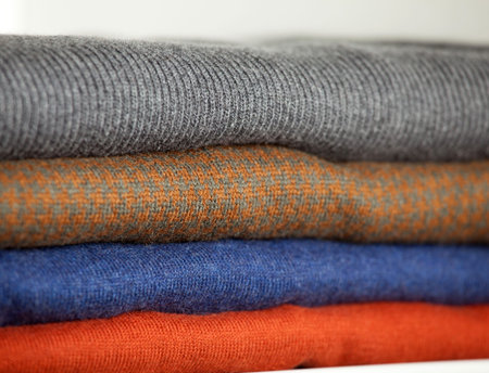 Stack of warm woolen clothes in a wardrobeの写真素材