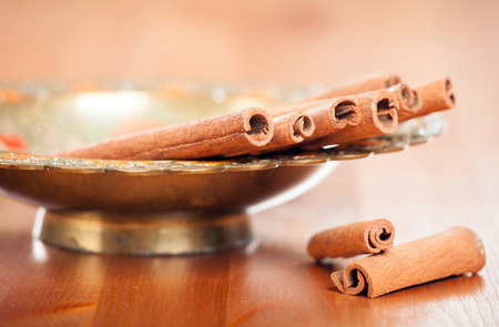 Cinnamon in a bronze decorative old-style dish on a wooden tableの写真素材