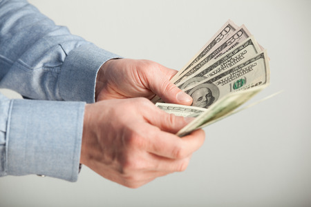 Unrecognizable man counting dollar banknotes - closeup shotの写真素材