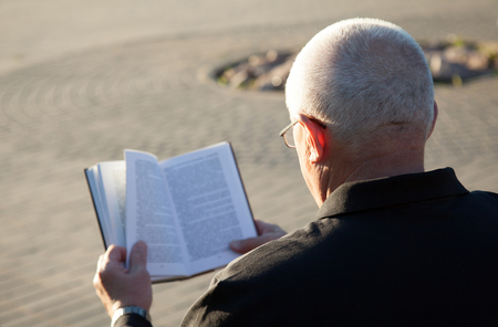 Rear view of a mature man reading a book outdoorsの写真素材