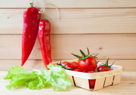 Composition of fresh raw vegetables: of red chili pepper, tomatoes and lettuce on wooden tableの写真素材