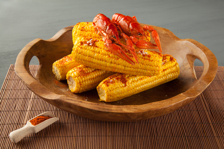 Boiled crayfish and sweet corns seasoned with ground cayenne pepper in a wooden bowlの写真素材