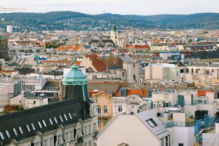Picturesque panoramic aerial view of Vienna skyline, city building roofs under the sunlite with the view of high hills around Viennaの写真素材