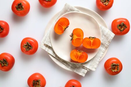 Persimmon still life, the whole and cut, served on the table, staying on the white background. Organic Kaki fruit harvested in autumn. Top viewの写真素材