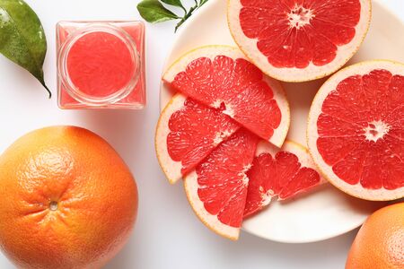 Fresh grapefruit juice in glass and sliced grapefruites on the white background, top viewの写真素材