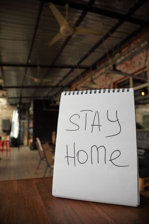 Stay home appeal written on a paper on the empty cafe tableの写真素材