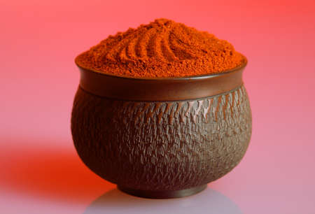 Red pepper powder in a beautiful bowl, red backgroundの写真素材