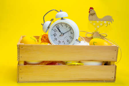 Colorful Easter eggs in a wicker basket and a wooden box on a yellow, green background. Space for textの写真素材