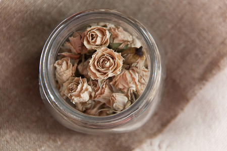 Dry roses for spa in glass bowl. Buds of dry roses in glass bottle on jute background の写真素材