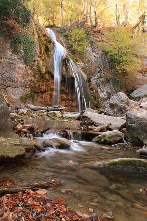 Autumn creek woods with yellow trees foliage and rocks in forest mountain.の写真素材
