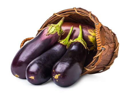 Ripe eggplants in wicker basket isolated on whiteの写真素材